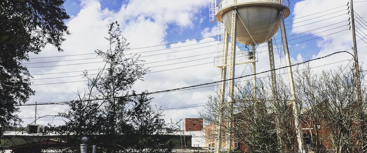 A water tower with 'INTEVILLE' and 'EST. 1845' on it, surrounded by a chain-link fence and trees.
