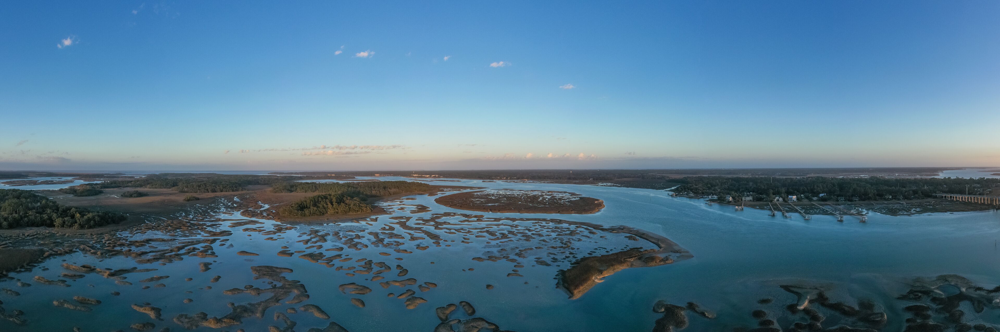 An aerial view of a river delta with multiple islands and a bridge in the distance.