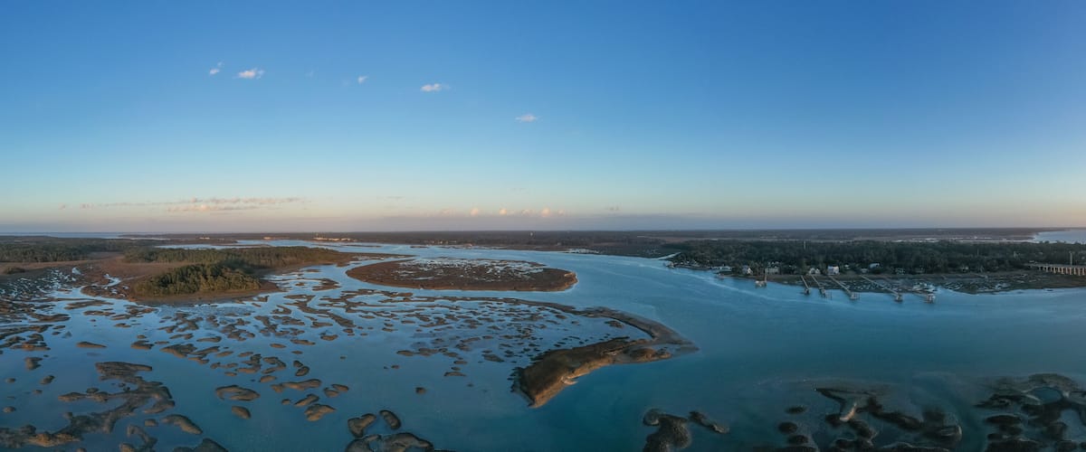 An aerial view of a river delta with multiple islands and a bridge in the distance.