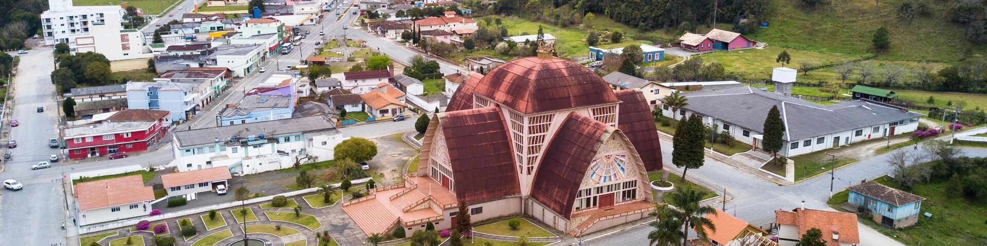 Vista aérea de un pueblo con una iglesia destacada, con una cúpula grande y una plaza central con una fuente.