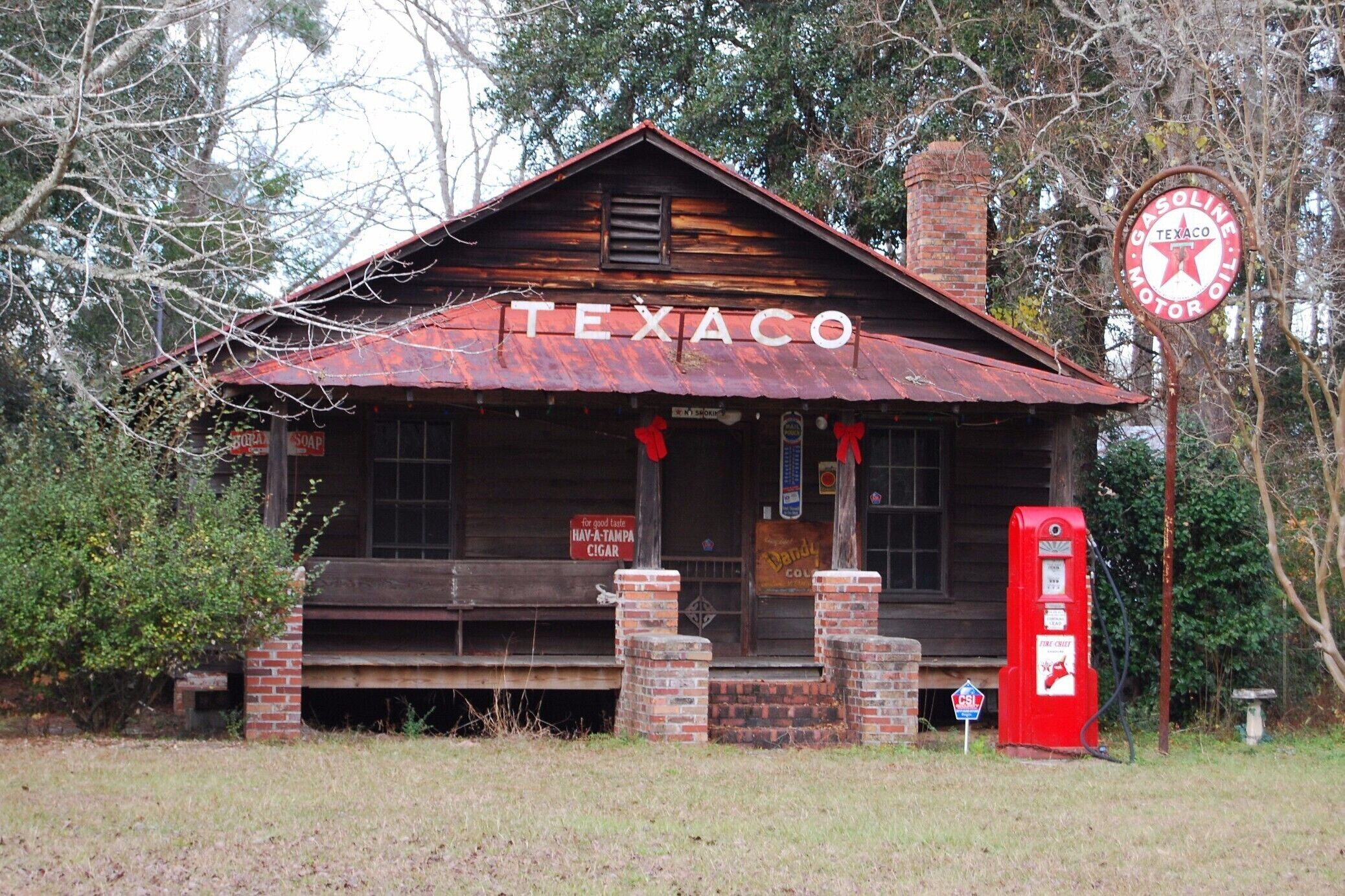 A rustic Texaco gas station with a wooden facade and a red roof, surrounded by trees.