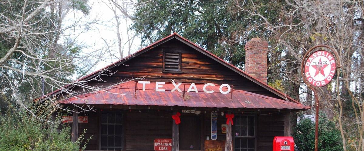 A rustic Texaco gas station with a wooden facade and a red roof, surrounded by trees.