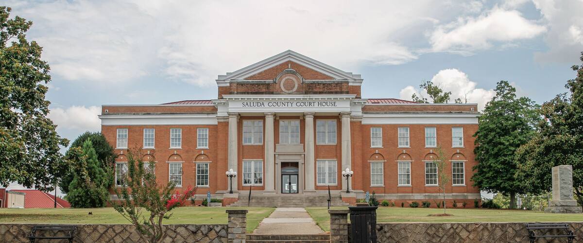 The exterior of the Saluda County Court House, featuring a symmetrical facade with a central entrance, large windows, and a brick structure.