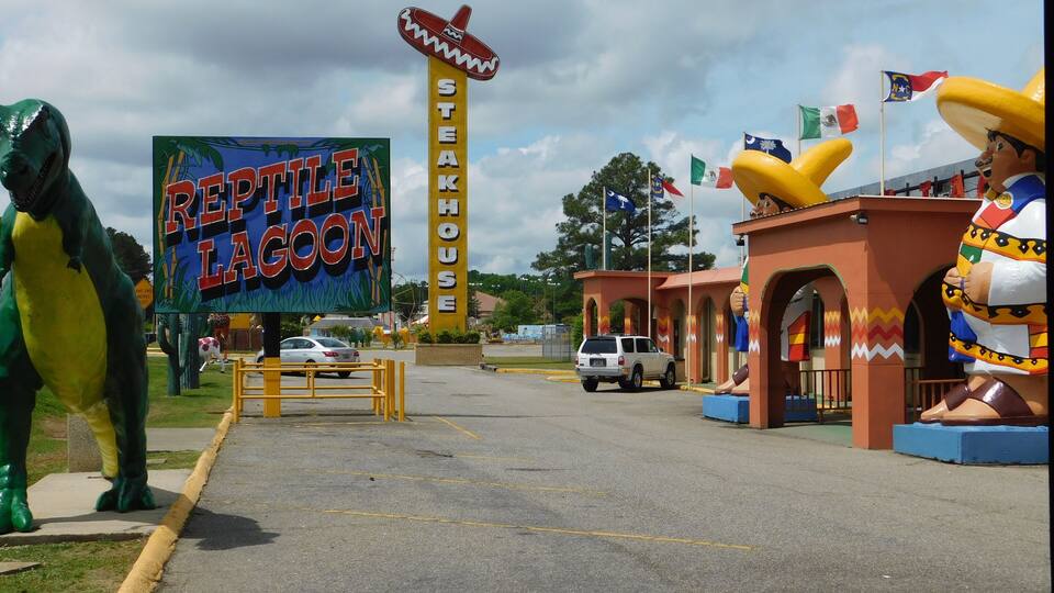 A parking lot with a sign for 'Reptile Lagoon' and a 'Steakhouse'.