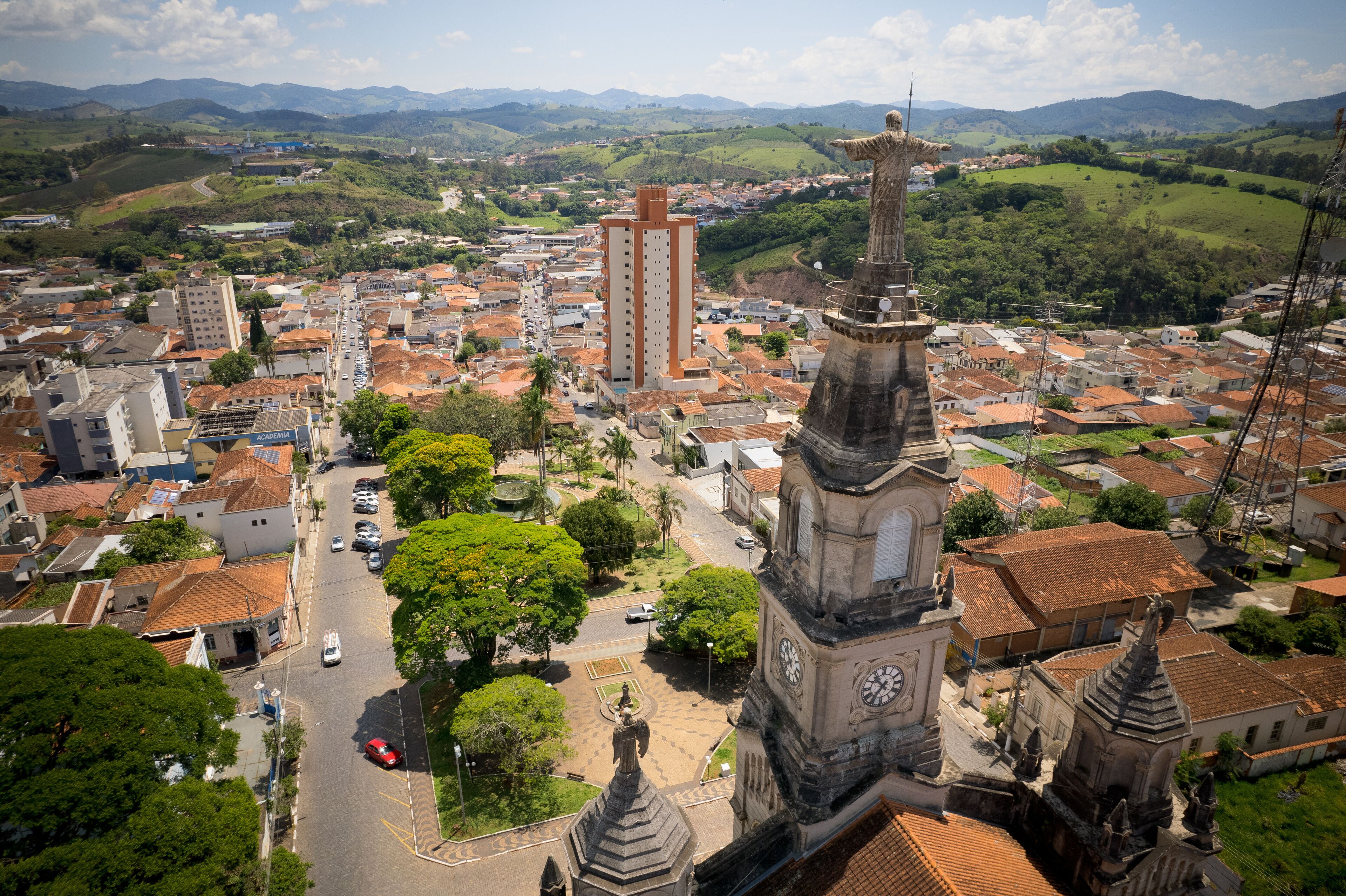 A town with a prominent church tower, lush green hills, and a mix of residential and commercial buildings.