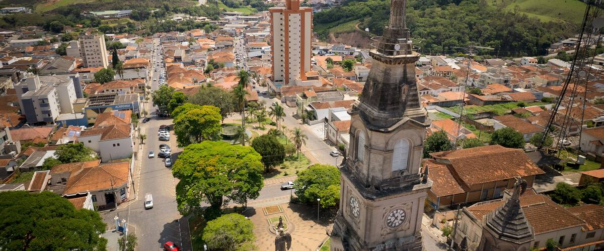 A town with a prominent church tower, lush green hills, and a mix of residential and commercial buildings.