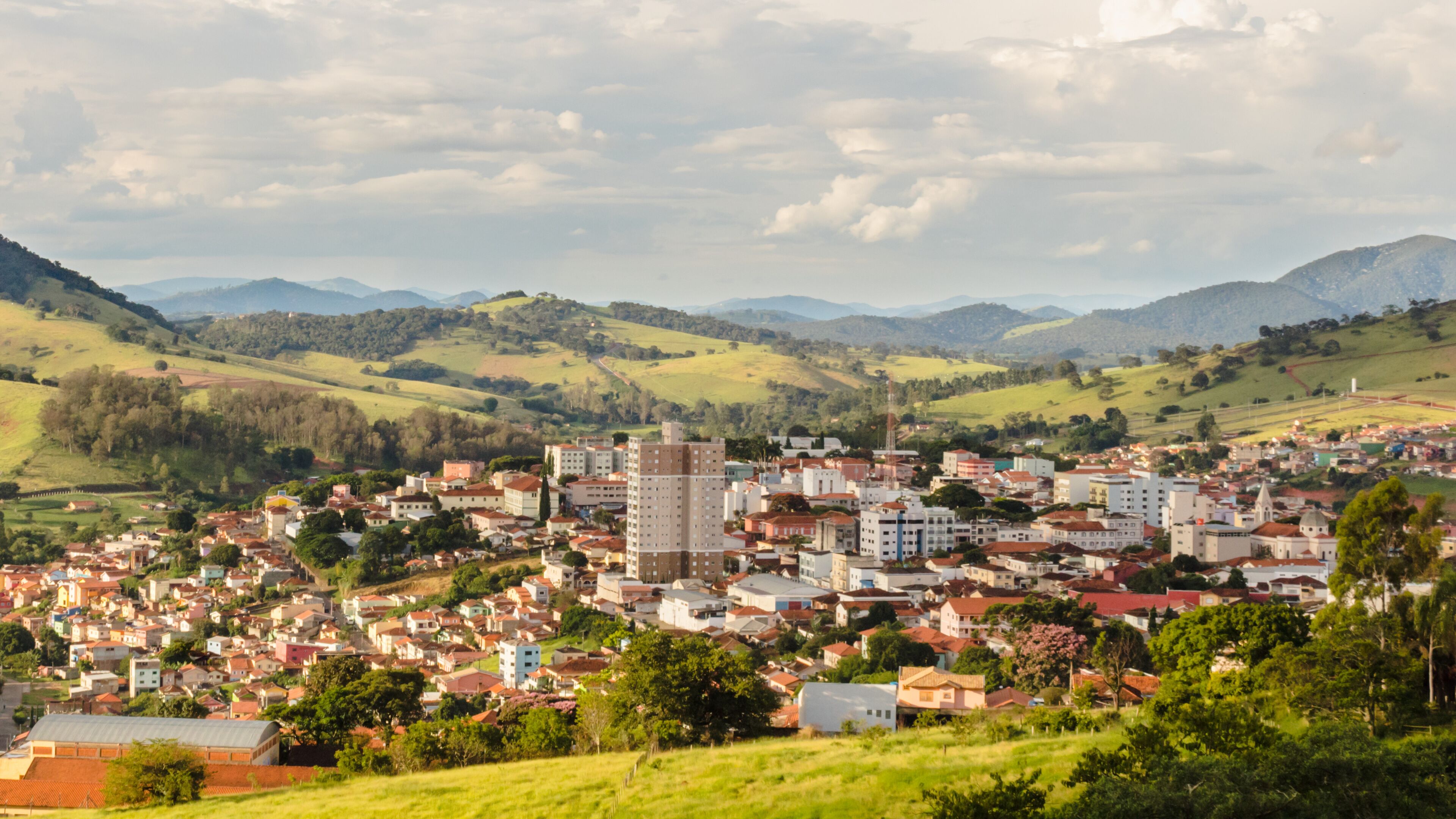 A town nestled in a valley with rolling hills and mountains in the background.