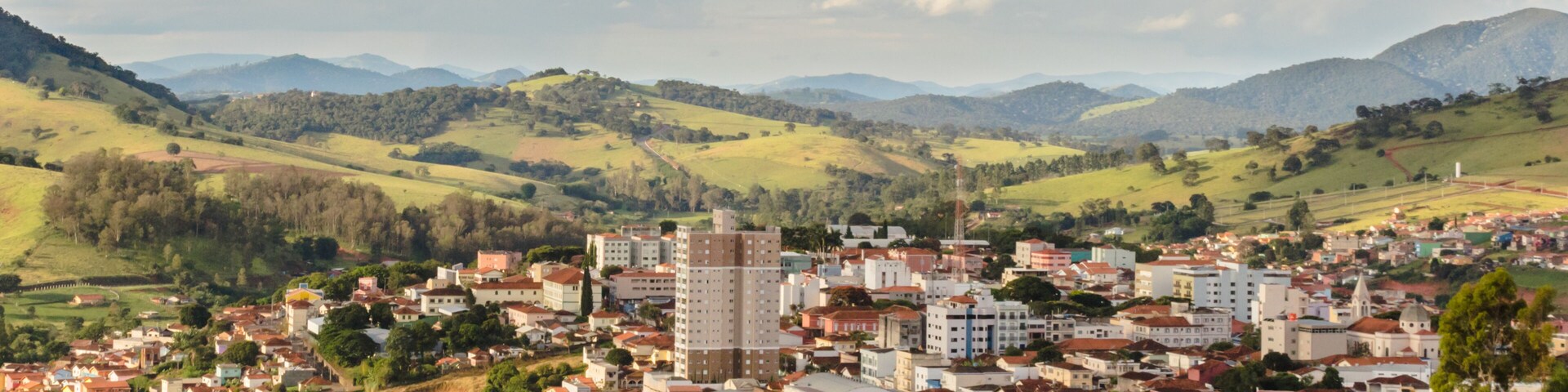 A town nestled in a valley with rolling hills and mountains in the background.