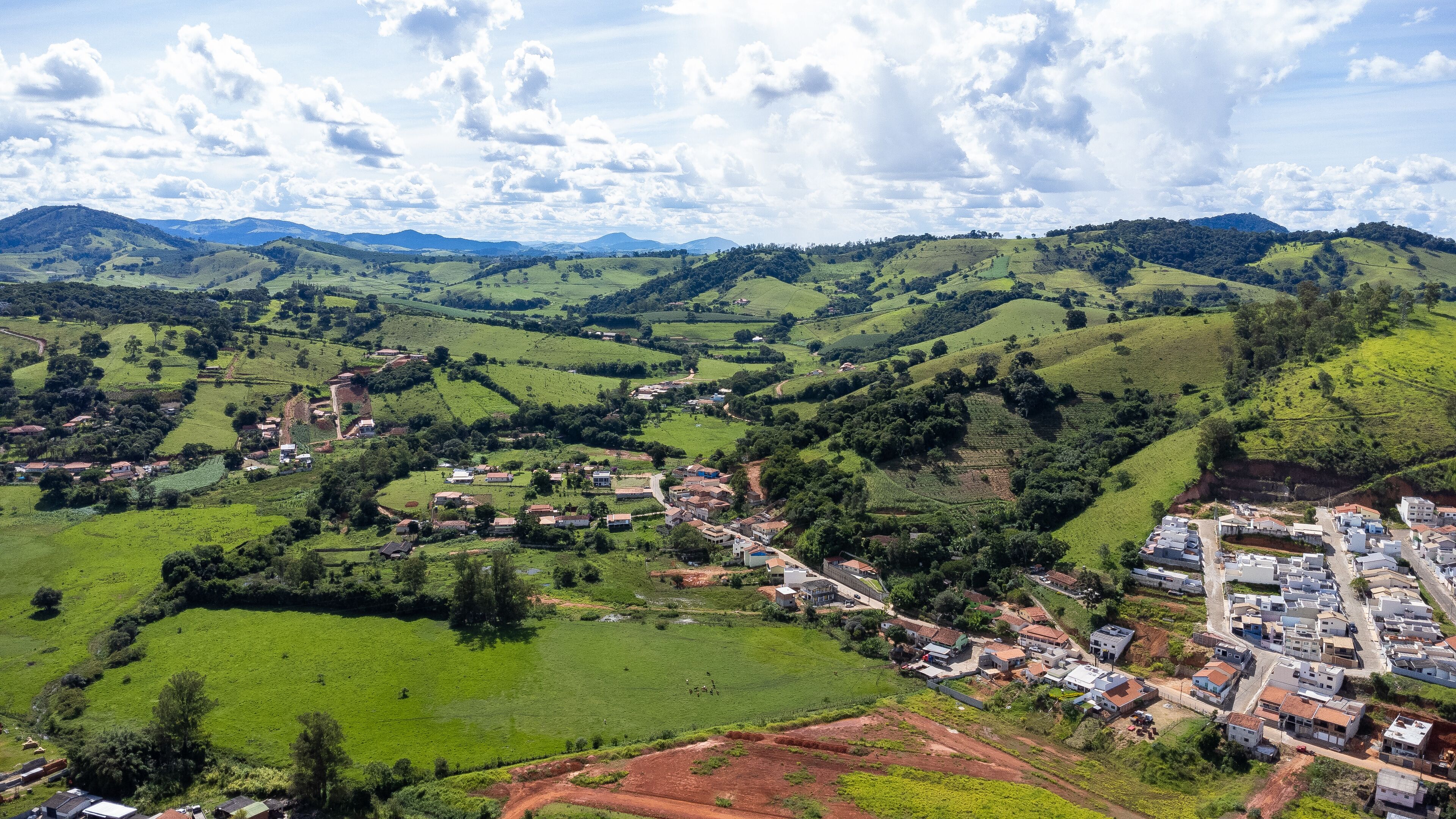 A rural landscape with rolling hills, scattered houses, and a small village nestled among the greenery.