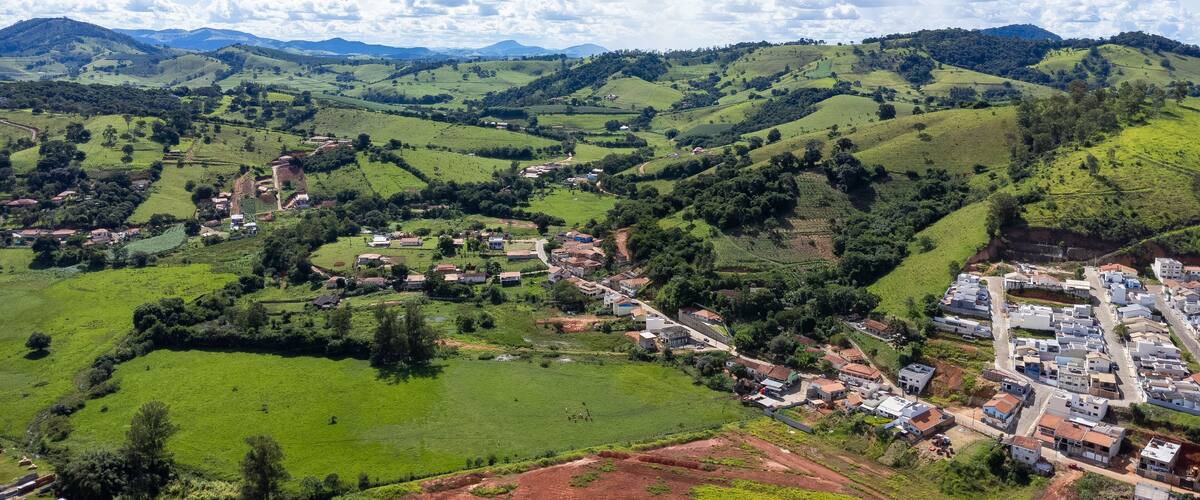 A rural landscape with rolling hills, scattered houses, and a small village nestled among the greenery.