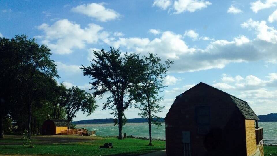 A rustic barn by a lake with a clear sky.