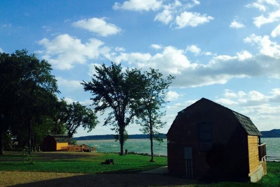 A rustic barn by a lake with a clear sky.