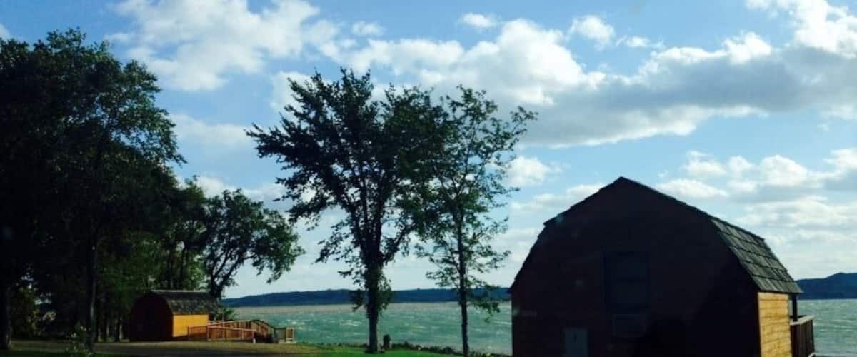 A rustic barn by a lake with a clear sky.