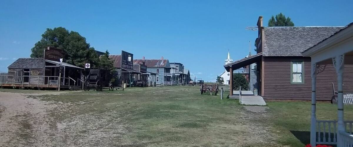 A historic town square with old buildings, a covered wagon, and a church.