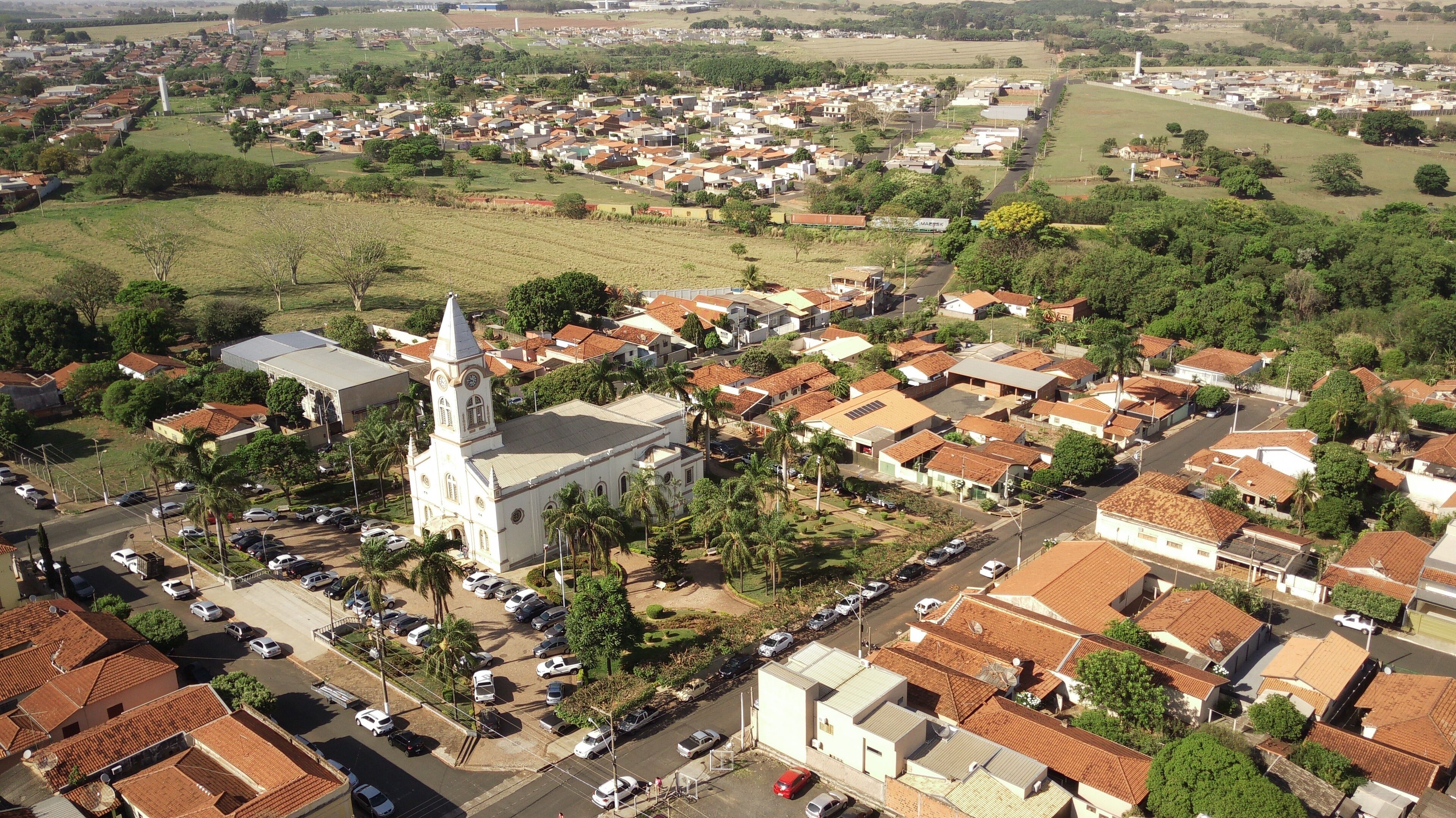 An aerial view of a town with a prominent church, residential areas, and surrounding greenery.