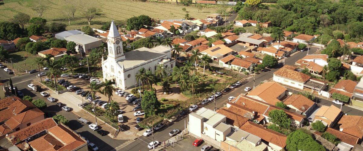 An aerial view of a town with a prominent church, residential areas, and surrounding greenery.