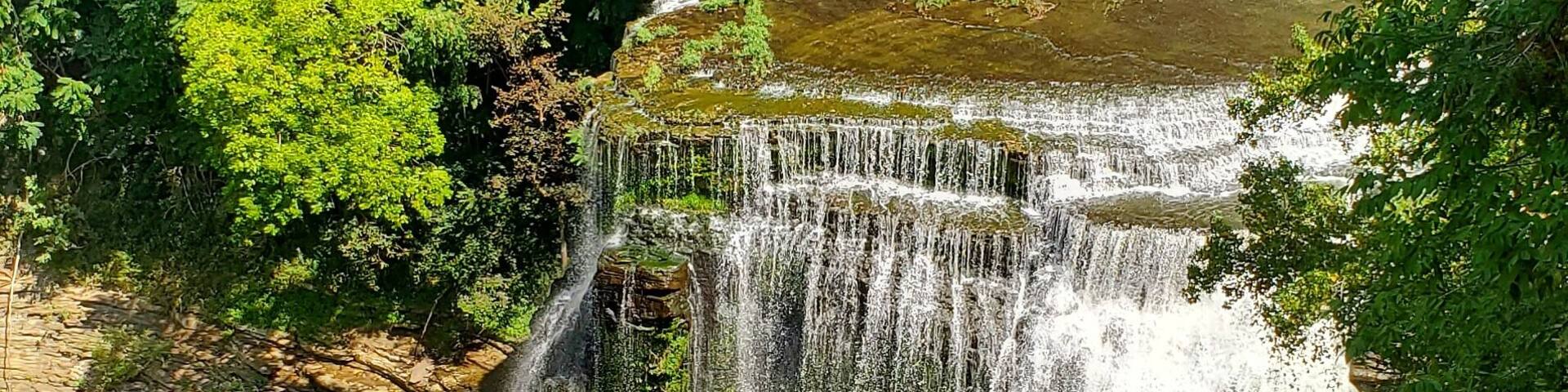 A multi-tiered waterfall surrounded by lush greenery.
