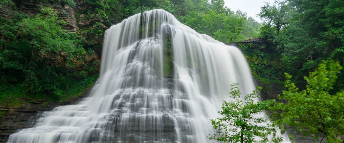 A multi-tiered waterfall surrounded by lush greenery.