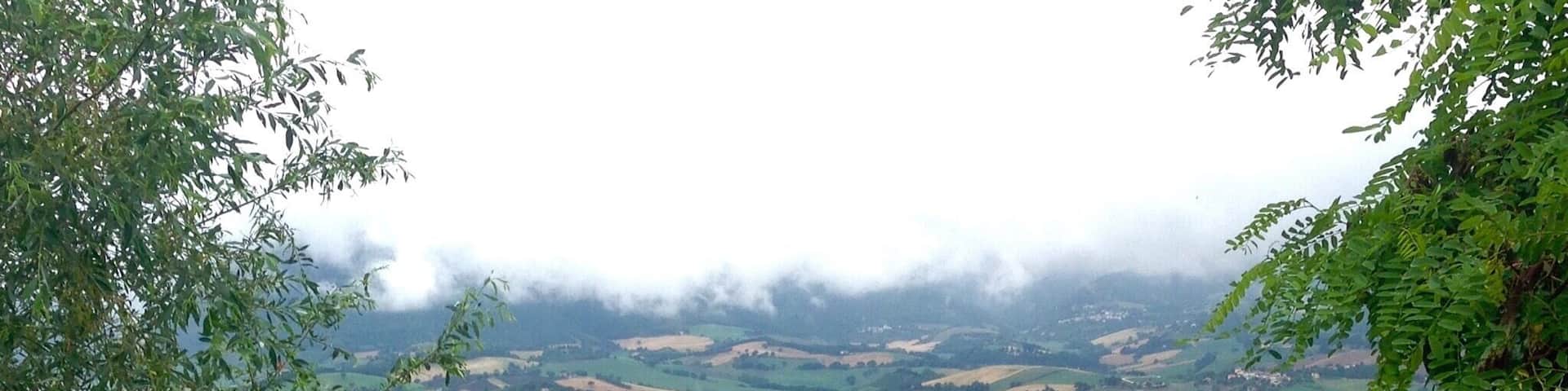 A lush valley with rolling hills, scattered houses, and dense greenery.