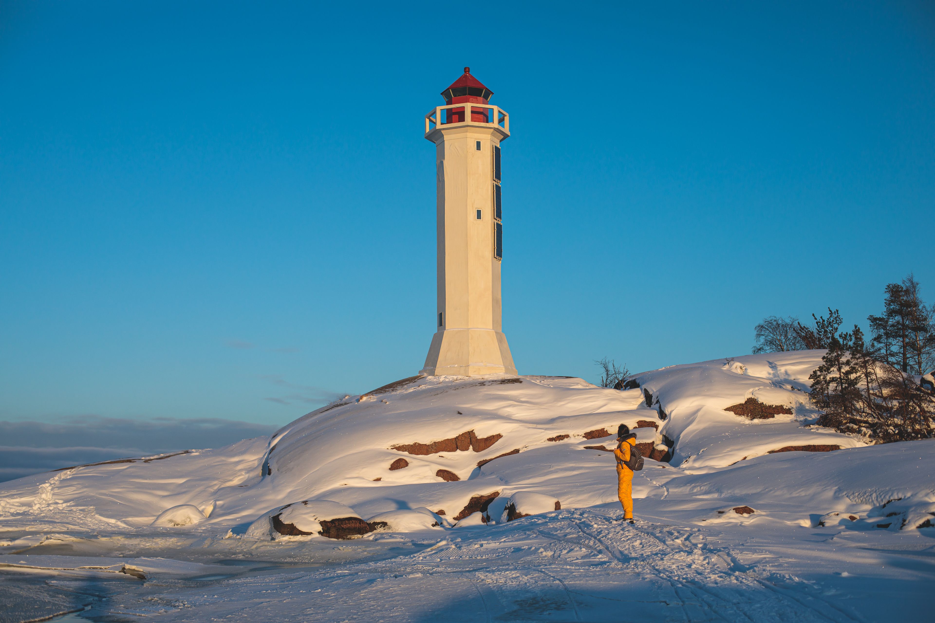 Un faro en una colina nevada bajo un cielo azul despejado.