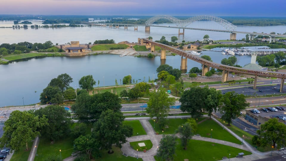 A river with a bridge, a park, and a historic building.