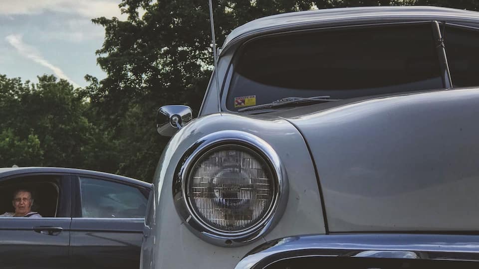 A vintage car with a round headlight and chrome details.