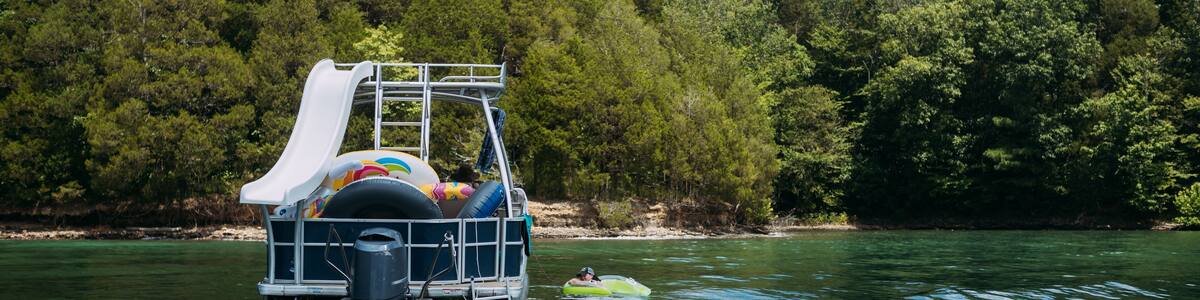 Woman floating next to pontoon boat in lake on summer day
