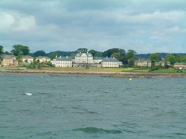 A waterfront with a large, historic building and several smaller houses.
