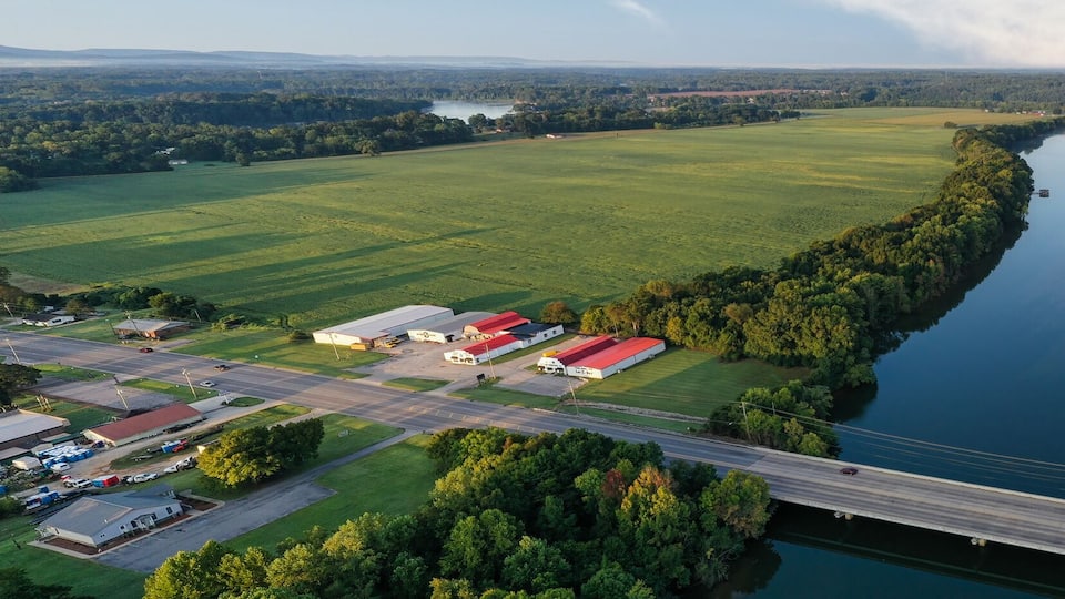 A river surrounded by fields, a bridge, and a parking lot.