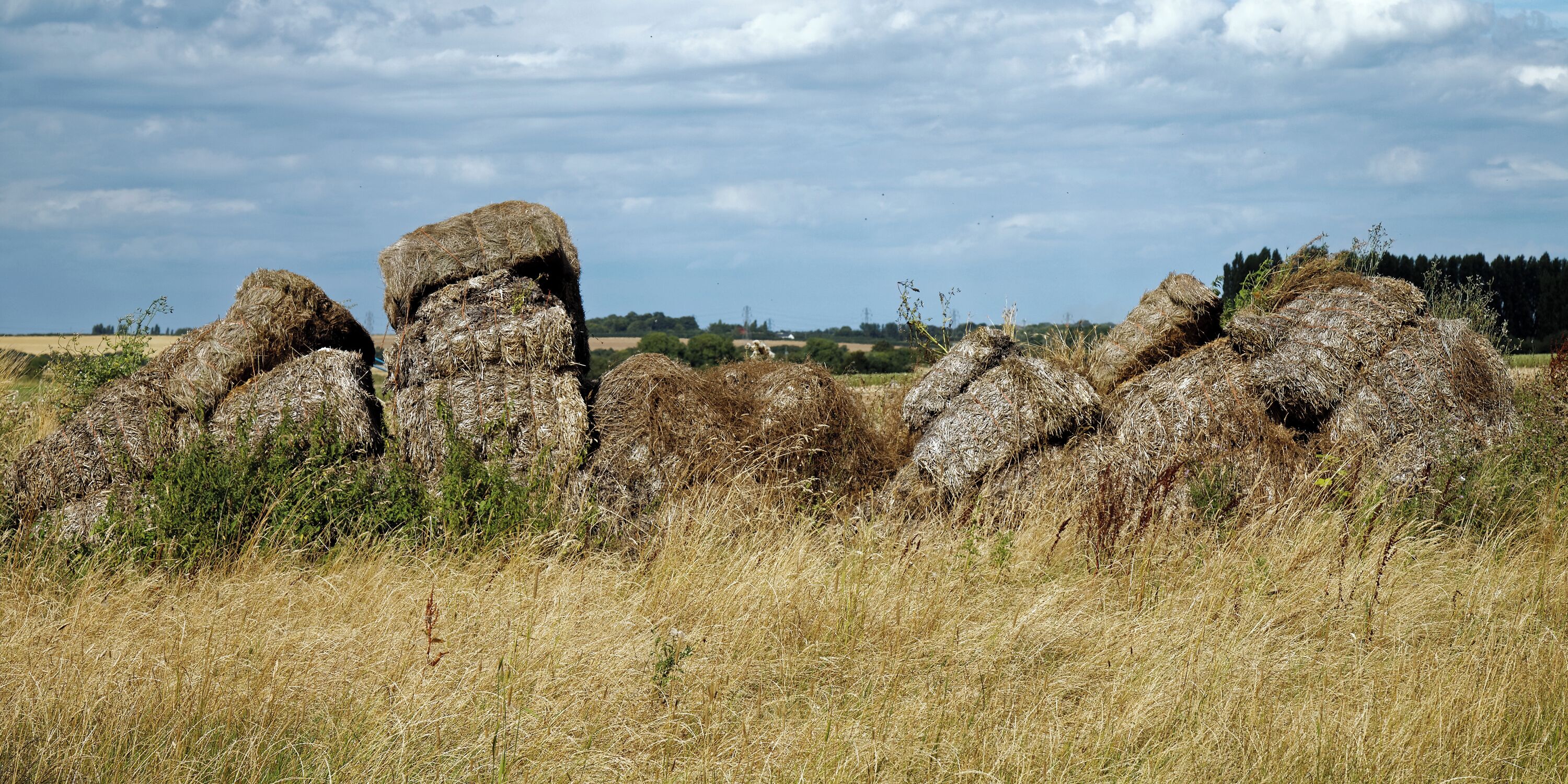 A field with hay bales and a large rock formation.