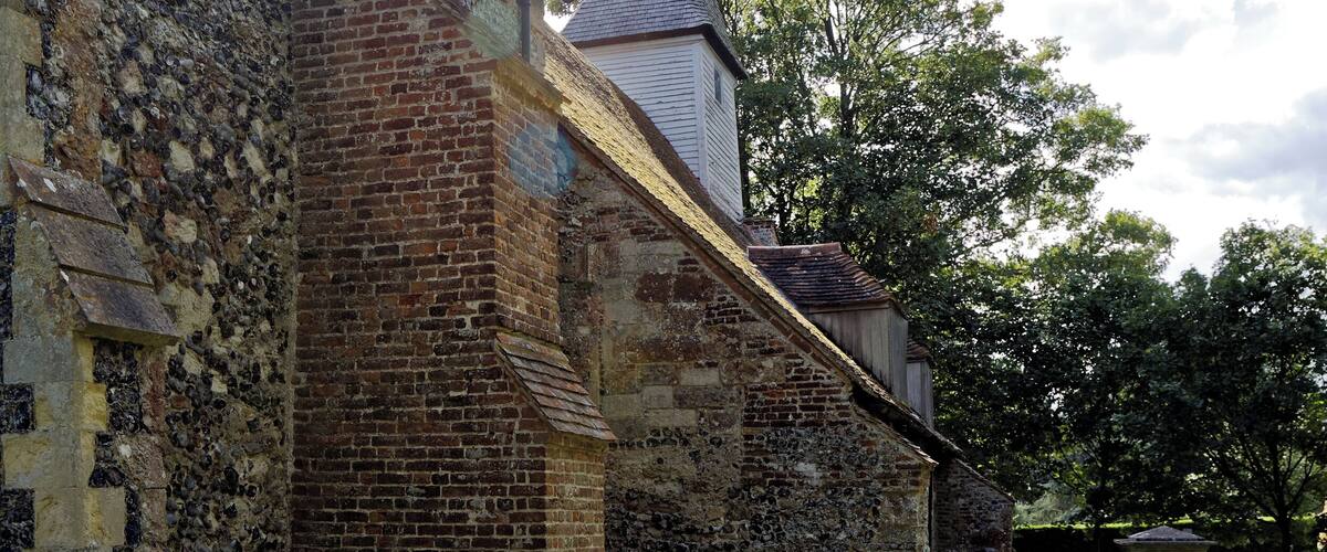 The weatherboard and shingle tower and broach spire, and buttressed chancel north wall, from the north-east of the churchyard of All Saints Church, West Stourmouth, in the civil parish of Stourmouth in Kent, England. Camera: Canon EOS 6D with Canon EF 24-105mm F4L IS USM lens. Software: RAW file lens-corrected, optimized, perhaps cropped, and converted to JPEG with DxO OpticsPro 11 Elite, and likely further optimized with Adobe Photoshop CS2.
