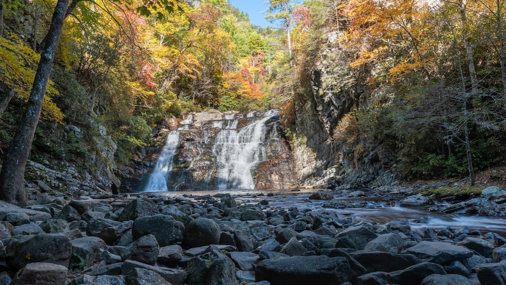Ein Wasserfall, umgeben von herbstlichem Laub.