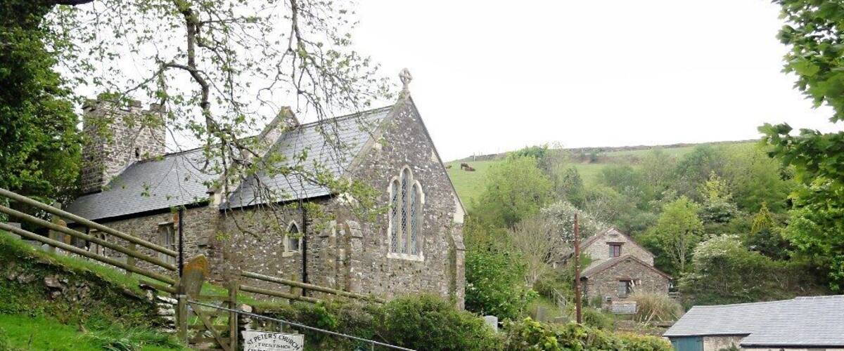 A rural road leading to a stone church with a sign indicating it is the church of St. Peter's Church, Churchcap Park, only.