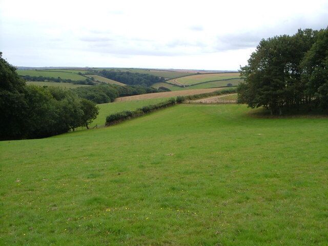 Buckland-tout-Saints Footpath 2. The view from the footpath as it crosses part of the parkland of the former Buckland House (now a hotel) below Buckland-tout-Saints church. The pond in 227108 is below the trees on the left. Cockshill Wood is a couple of fields away; in the distance is the wood near Ranscombe (see 226602).