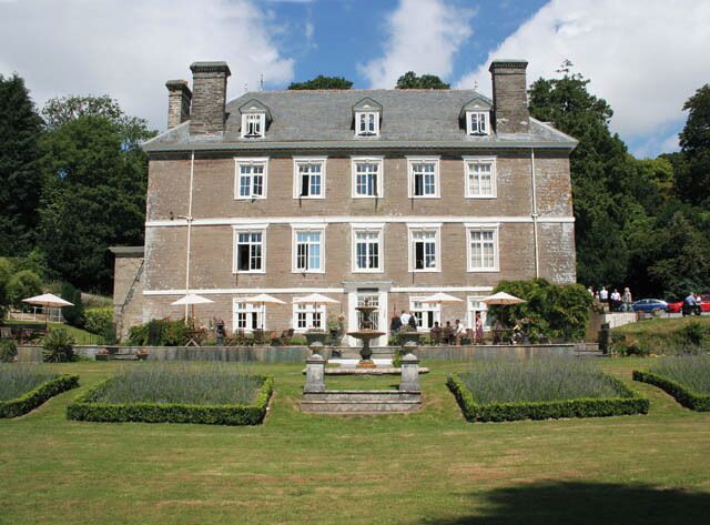 A large stone building with a symmetrical facade, multiple windows, and a central entrance.