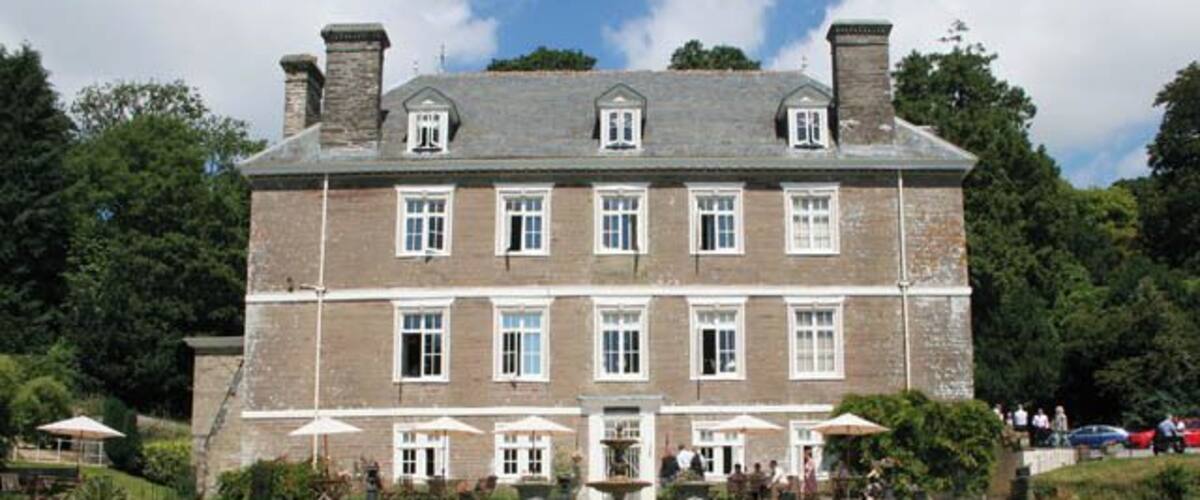 A large stone building with a symmetrical facade, multiple windows, and a central entrance.