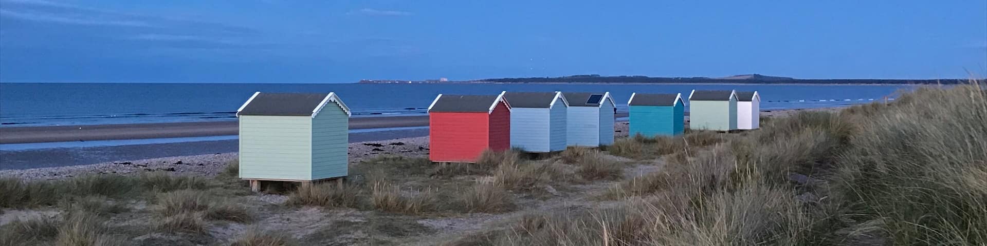 A row of colorful beach huts along a coastal path.