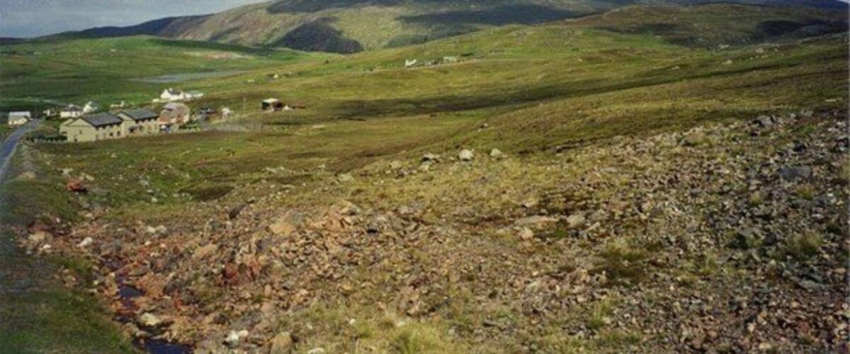 Paisaje rural con colinas ondulantes, un pequeño poblado y una carretera.