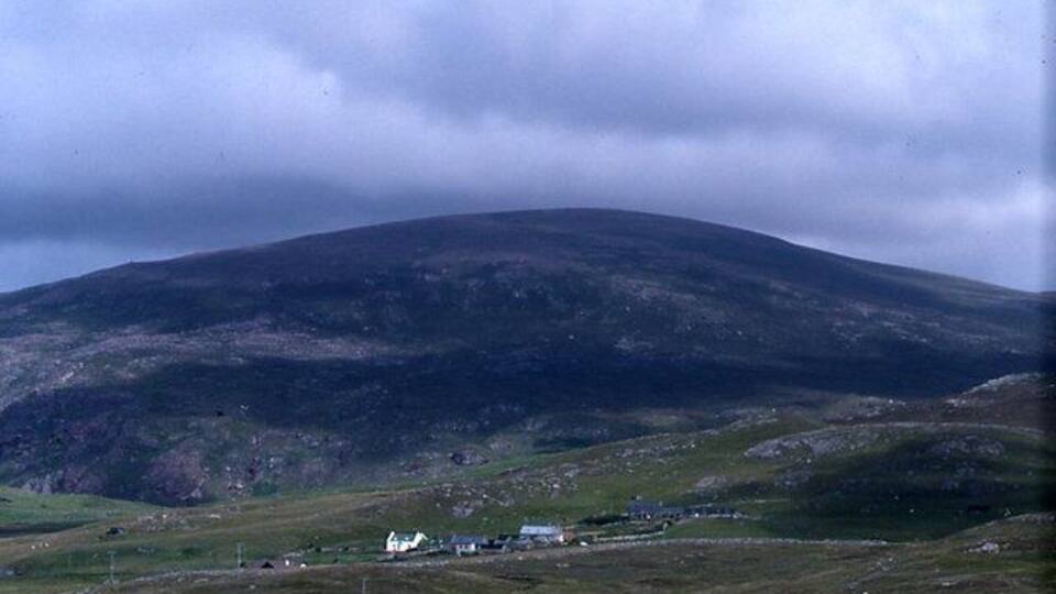 A mountain with a small settlement at its base.