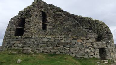 A stone ruin with two visible openings, surrounded by grassy terrain.