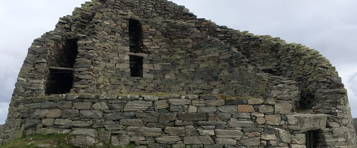 A stone ruin with two visible openings, surrounded by grassy terrain.