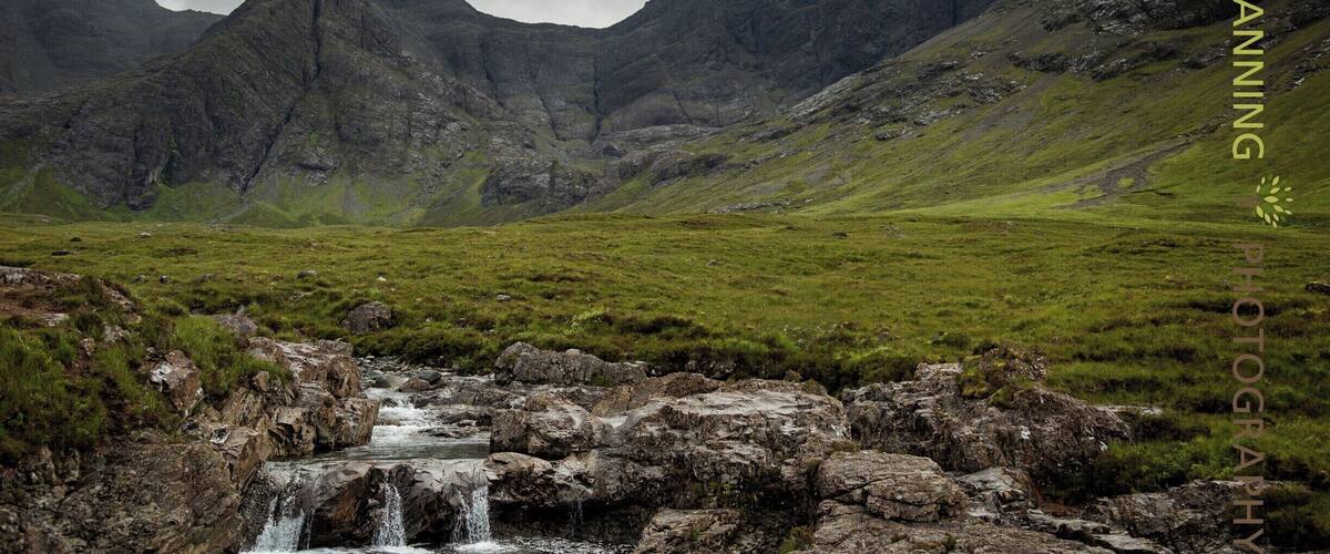 A mountainous landscape with a waterfall flowing over rocks.