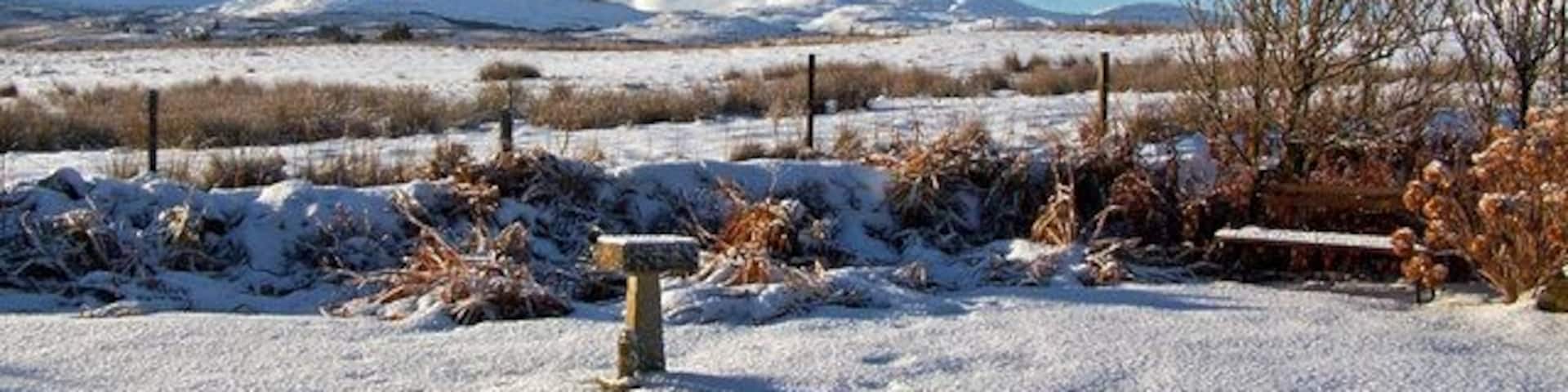Garden and view, January 2010 A covering of snow and bright winter sunshine. A long shadow is being cast from the birdbath in my garden in Roskhill near Dunvegan. The view is south west, with Healabhal Bheag just right of centre and Beinn na Boineid to the far left. (Just for the record, this is my 3,999th Geograph submission).