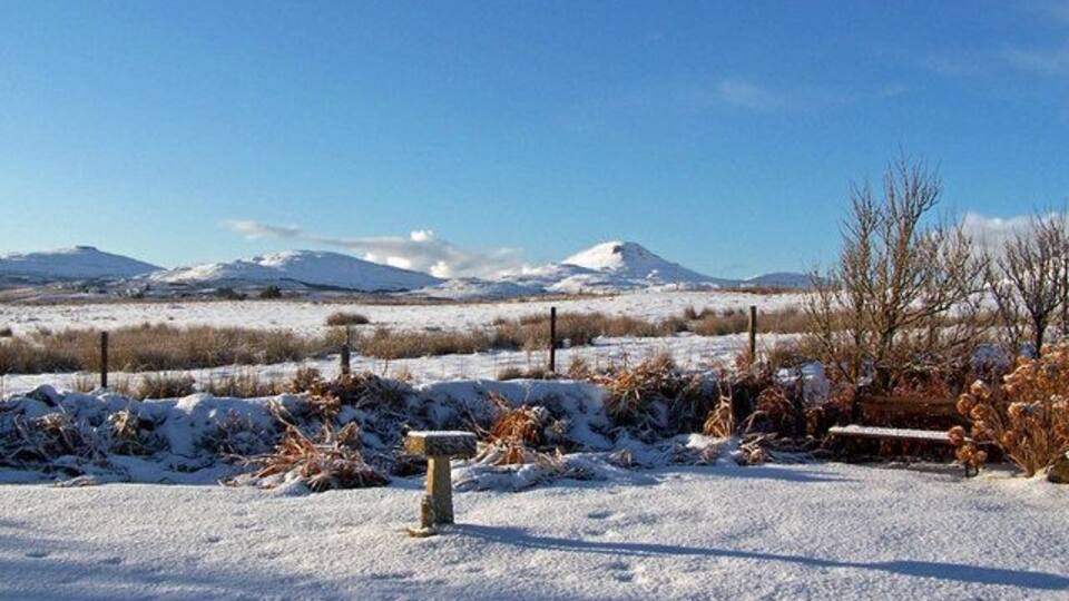 Garden and view, January 2010 A covering of snow and bright winter sunshine. A long shadow is being cast from the birdbath in my garden in Roskhill near Dunvegan. The view is south west, with Healabhal Bheag just right of centre and Beinn na Boineid to the far left. (Just for the record, this is my 3,999th Geograph submission).