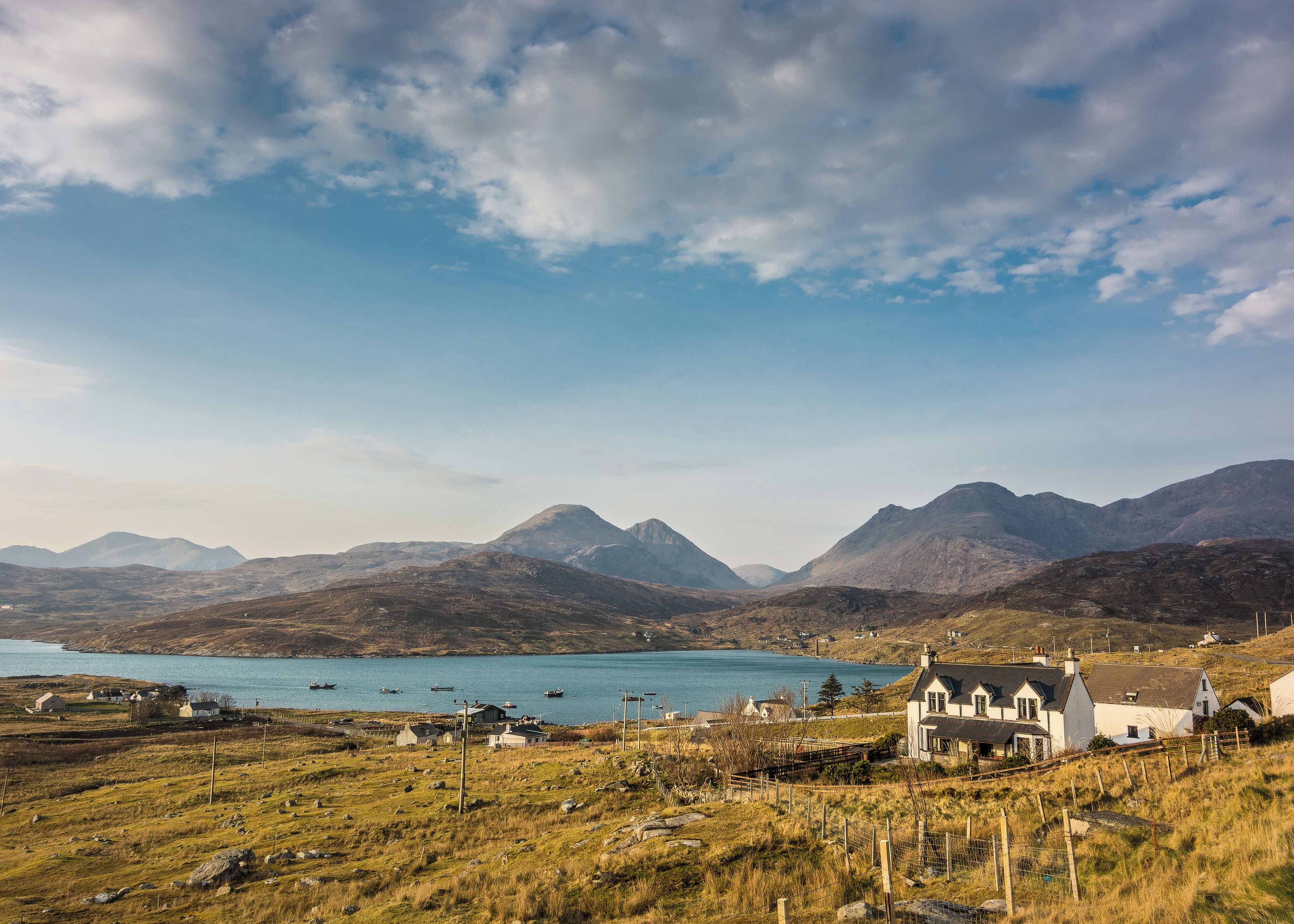 A coastal village with houses, a church, and mountains in the background.
