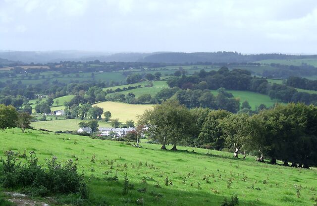 Rolling green hills, a small village, and scattered trees.
