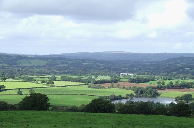 Rolling green hills, a river, and distant hills.