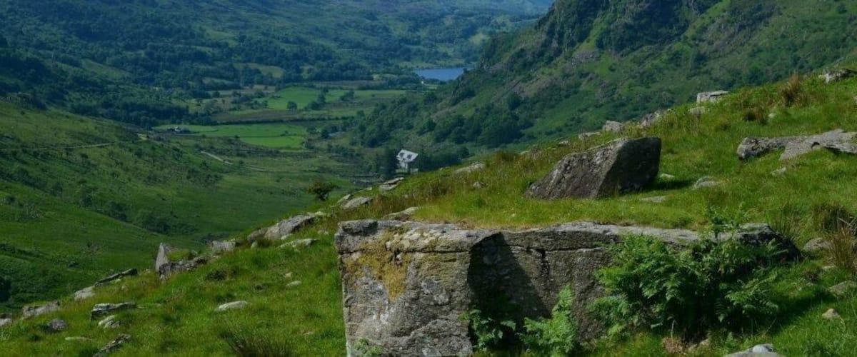A valley with a lake, green hills, and a stone structure.