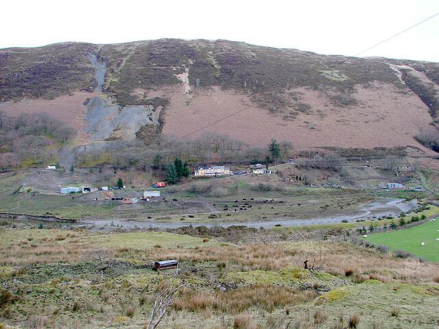 A rural landscape with a hill, a small village, and a stream.