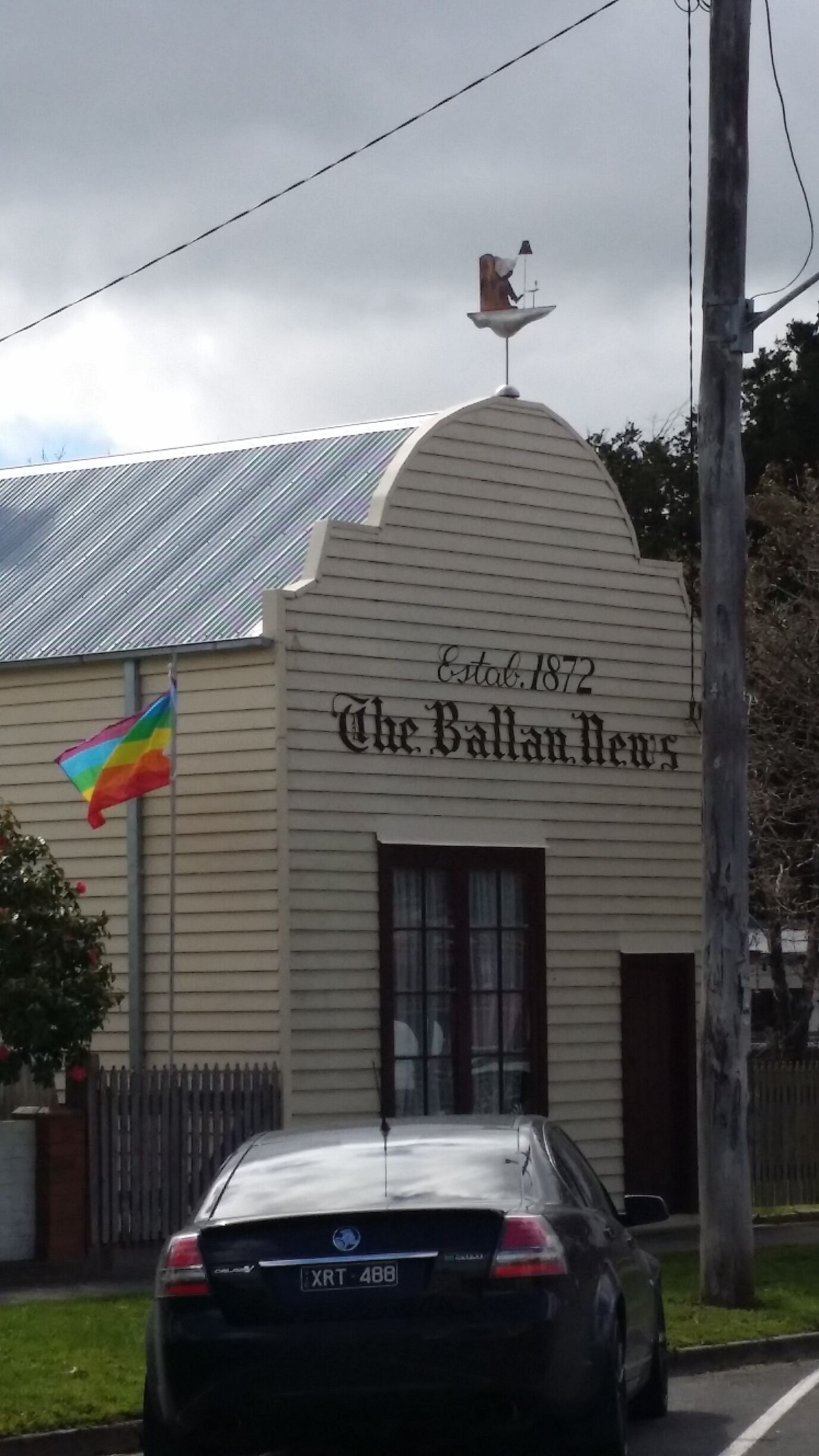 A building with a sign reading "The Ballan News" and a rainbow flag.